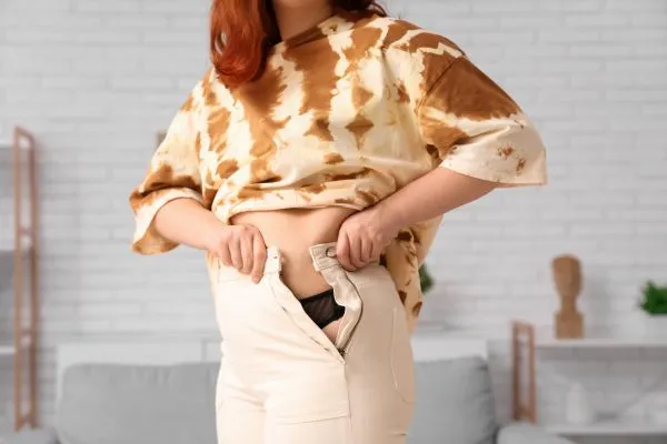 Image of woman trying to do her trousers up after pregnancy weight gain Rotherham
