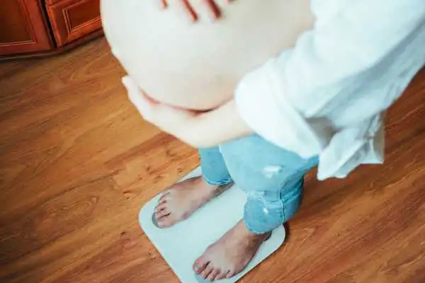 Image of woman weighing herself and experiencing weight gain through pregnancy Rotherham